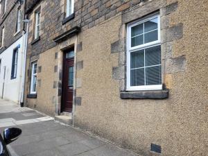 un edificio de ladrillo con una ventana y una puerta en Cameronian Apartment, en Stirling