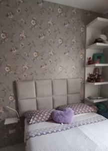 Un dormitorio con una cama con un animal de peluche púrpura. en Apartamento 2 quartos aconchegante en Santos