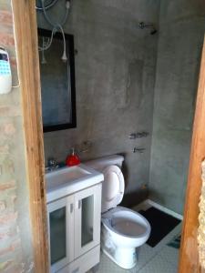 y baño con aseo, lavabo y espejo. en Cabaña LA PEDRERA - Pileta y a metros del Rio en Bialet Massé