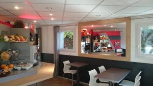 a restaurant with a table and chairs and a counter at A&H PRIVILÈGE Lyon Est - Saint Priest Eurexpo in Saint-Priest