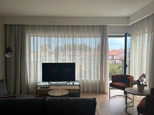 a living room with a television and a large window at Leça Apartments in Leça da Palmeira