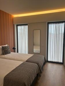 een hotelkamer met 2 bedden en een spiegel bij Leça Apartments in Leça da Palmeira