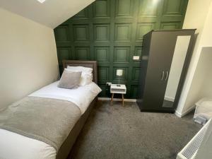 een slaapkamer met een bed en een groene muur bij Elegant 3 Bedroom Apartment in Rowley Regis