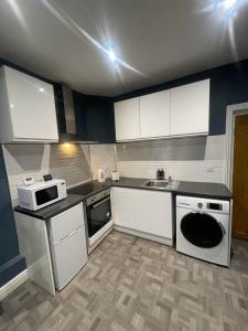 a kitchen with white cabinets and a sink at Elegant 3 Bedroom Apartment in Rowley Regis