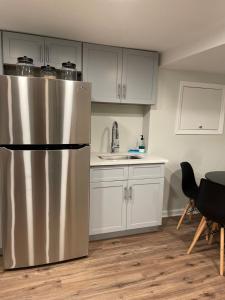 a kitchen with a stainless steel refrigerator and white cabinets at My little place in Stratford