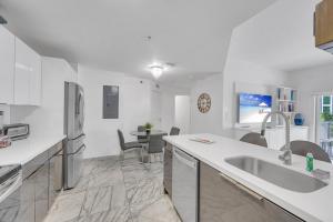 a white kitchen with a sink and a refrigerator at Subtle 2 Bed in Edgewater near Downtown With Free Parking in Miami
