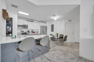 a white kitchen with white chairs and a counter at Subtle 2 Bed in Edgewater near Downtown With Free Parking in Miami