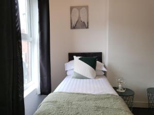 una camera da letto con un letto con cuscini bianchi e verdi di Lovely Coventry Home - Suitable for Business, Contractors, Families, Relocators, mins walk to City Centre and University a Wyken