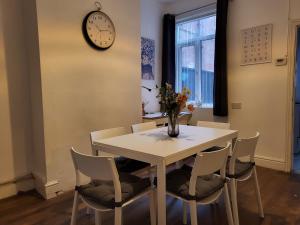 a dining room table with chairs and a clock on the wall at Lovely Coventry Home - Ideal for Business, Contractors, Families, Relocators mins walk to City Centre and University in Wyken
