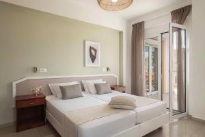 a bedroom with a large white bed and a window at Artemis Apartments in Stalos