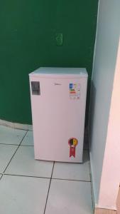 a white refrigerator in a room with a green wall at Casa Aconchegante in Marabá +5 photos
