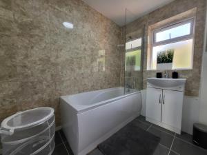 uma casa de banho com uma banheira branca e um lavatório. em Stylish Flat - Great location for Contractors, Families, Relocators, Business, Free Parking, Long-Stays em Banbury