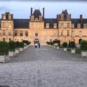 two people walking in front of a large building at Studio Le Mansart au pied du Château Insead in Fontainebleau