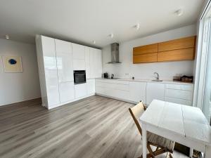 cocina con armarios blancos, mesa y comedor en Luxury apartment Mýrargata - Birta Rentals, en Reikiavik