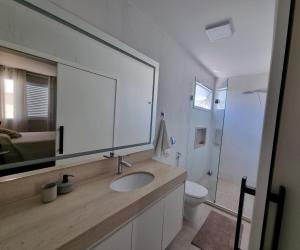 ein Badezimmer mit einem Waschbecken, einem Spiegel und einem WC in der Unterkunft Casa Fontán in São Lourenço