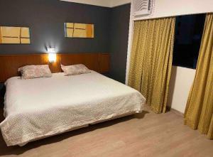 1 dormitorio con cama blanca y cortinas amarillas en Flat Live Lodge, en São Paulo