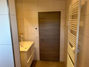 a bathroom with a sink and a wooden door at Green hills holiday house in Warmensteinach