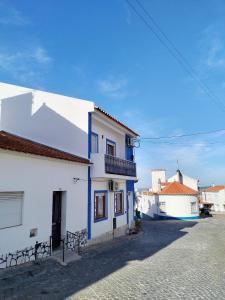 a white building with blue trim on a street at Casa da laranjeira in Montargil
