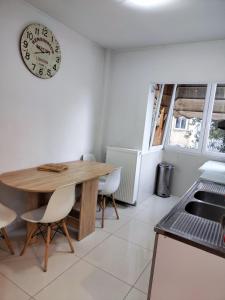 a kitchen with a wooden table and chairs and a clock at 4ALL Airport 10min,Sea100m,Free parking in Thessaloniki
