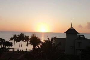 un tramonto sull'oceano con una chiesa e palme di Sunset View La Cote D 'Azure a Pereybere