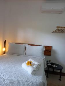 Un dormitorio con una cama con una toalla y una flor. en Suítes Mathias flat en Conservatória