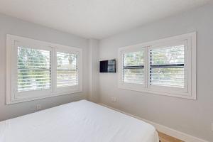 a white bedroom with two windows and a bed at Enclave 2202 in Orlando