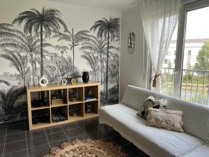 a living room with a couch and palm trees mural at Appartement à 5 min de DISNEY proche PARIS in Chanteloup-en-Brie