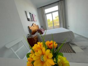 a bedroom with a bed and a vase of flowers on a table at El Coloso de SteraM Flats Benalmádena in Benalmádena