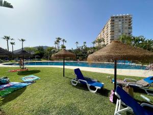 a group of chairs and umbrellas next to a swimming pool at El Coloso de SteraM Flats Benalmádena in Benalmádena