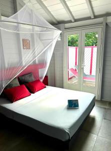 Una cama con mosquitera encima. en Caraïbes Cottage Grenat piscine privée 900m de Grande anse, en Deshaies