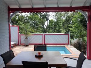 patio ze stołem i krzesłami oraz basenem w obiekcie Caraïbes Cottage Grenat piscine privée 900m de Grande anse w mieście Deshaies