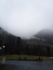 Una vista de una montaña envuelta en niebla con un estacionamiento. en l'orée du bois appartement t3, en Cauterets 1 foto más