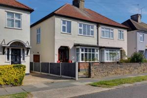 a white house with a fence in front of it at Grove House Southend on Sea in Southend-on-Sea