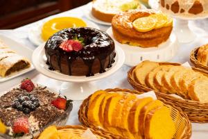 a table filled with different types of cakes and pastries at Pousada Valle das Flores Monte Verde in Monte Verde