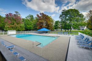 uma piscina com cadeiras e um guarda-sol azul em All-Season Warren Mountain Escape Near Sugarbush! em Warren