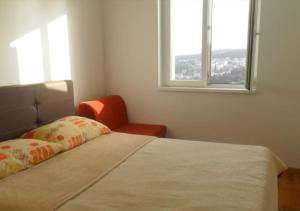 1 dormitorio con 1 cama con silla y ventana en Apartment ANELA with large balcony and beautiful sea view, en Dubrovnik