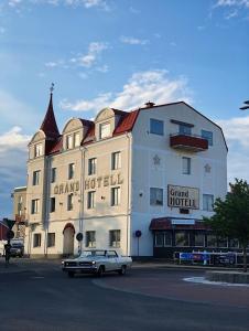 un coche blanco estacionado frente a un gran edificio en Grand Hotell en Strömsund