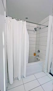 a bathroom with a white shower curtain and a tub at Stunning Luxurious LakeView Condo by CN Tower in Toronto