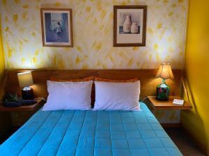 een slaapkamer met een blauw bed met 2 lampen en 2 foto's bij CABAÑAS DE LA LUNA in Los Molles