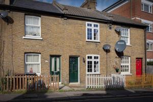 a brick house with a red door and a fence at Roman Cottage Chelmsford in Chelmsford