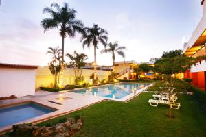 a backyard with a swimming pool and palm trees at Hotel Puerta Del Sol Guadalajara in Guadalajara