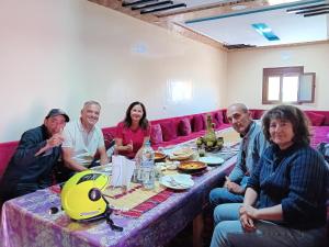 un grupo de personas sentadas alrededor de una mesa en Maison D'hôtes Chez Bassou Agoudal, en Agoudal