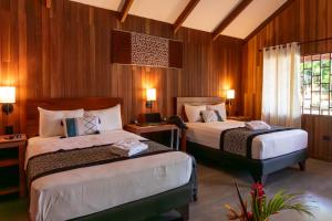 two beds in a room with wooden walls at WAKAYA ECOLODGE in Pucallpa