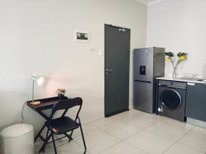 eine Küche mit einer Waschmaschine und einem Schreibtisch mit einem Stuhl in der Unterkunft Bounce Modern Home of Top Comfort in Midrand