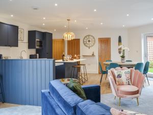 a living room and kitchen with a blue couch at West Lodge in Sewerby