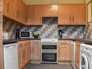 a kitchen with wooden cabinets and white appliances at Swallowdale Cottage in Levisham