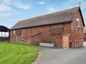 a red brick building with a grass yard next to it at The Barn in Nantwich