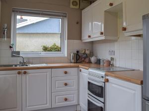 a kitchen with white cabinets and a sink and a window at Maes Dyfed in St. Davids