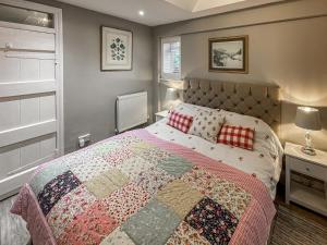 a bedroom with a bed with a quilt on it at Acorn Cottage in Linton