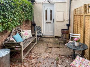 un patio con banco, mesa y puerta en Acorn Cottage en Linton